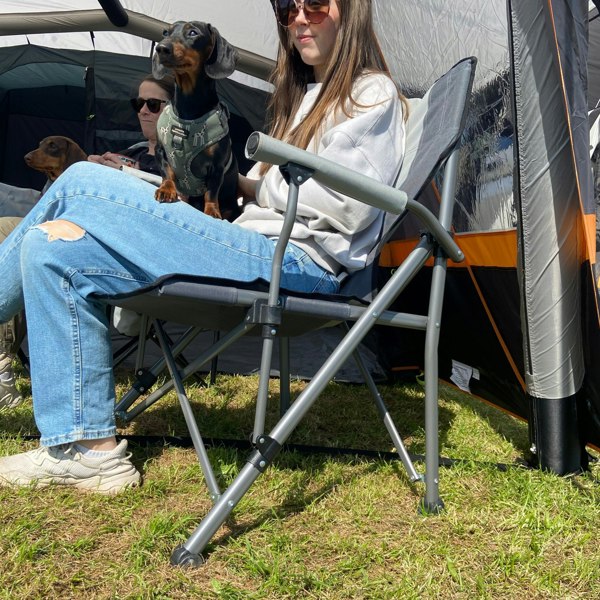 An image of an adult sat on the Denali Deluxe Camp Chair from OLPRO inside the front porch of a tent.