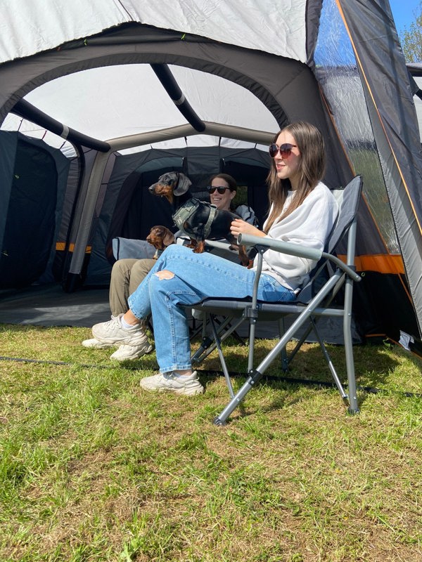 An image of an adult sat on the Denali Deluxe Camp Chair from OLPRO inside the front porch of a tent.