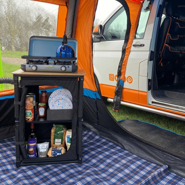 The OLPRO Bamboo Cooking Table with plates, cutlery and food in it in a campervan awning.