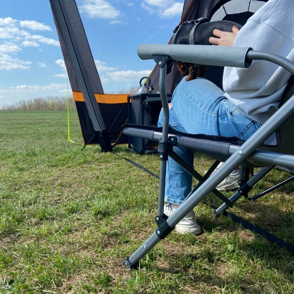 An image of an adult sat on the Denali Deluxe Camp Chair from OLPRO inside the front porch of a tent.