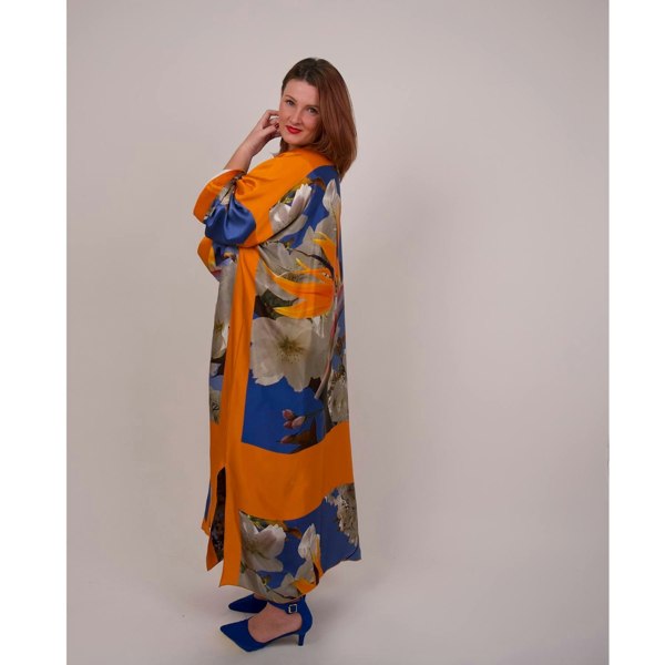 Model showcases the Bird of Paradise Cherry Blossom Silk Kimono from the side while wearing blue shoes, emphasizing the vibrant colors and elegant design.