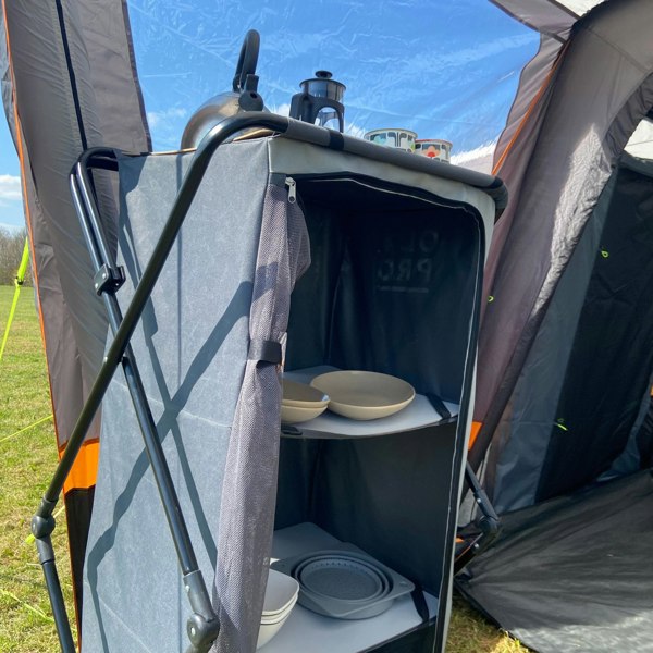 An image of the Collapsible Camp Storage Cupboard from OLPRO in a campervan awning pitched on a campsite.