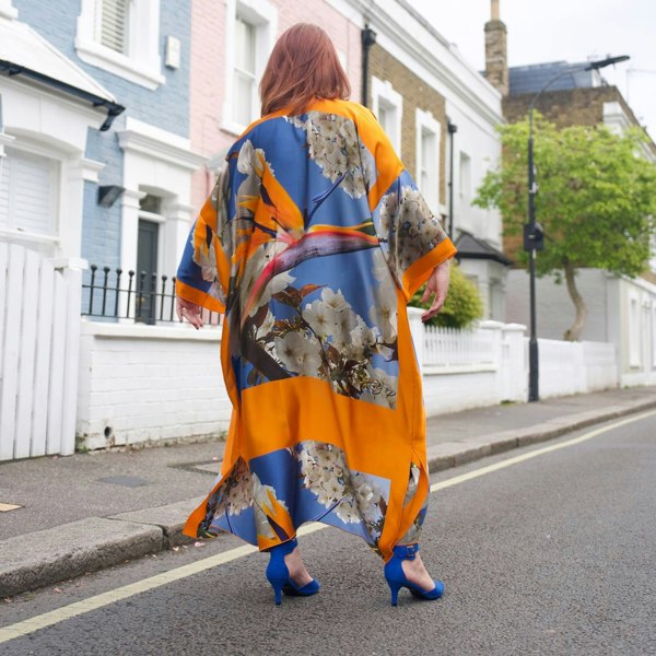 Model showcases the Bird of Paradise Cherry Blossom Silk Kimono from the back while wearing blue shoes, emphasizing the vibrant colors and elegant design.