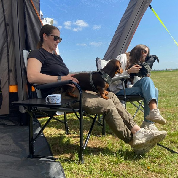 A picture of a mother and a daughter sat on the OLPRO Directors Camping Chairs whilst on a campsite in the porch of there tent.