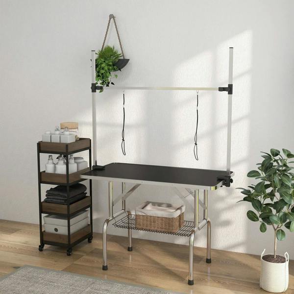 Adjustable pet grooming table with black rubber top and wire storage basket