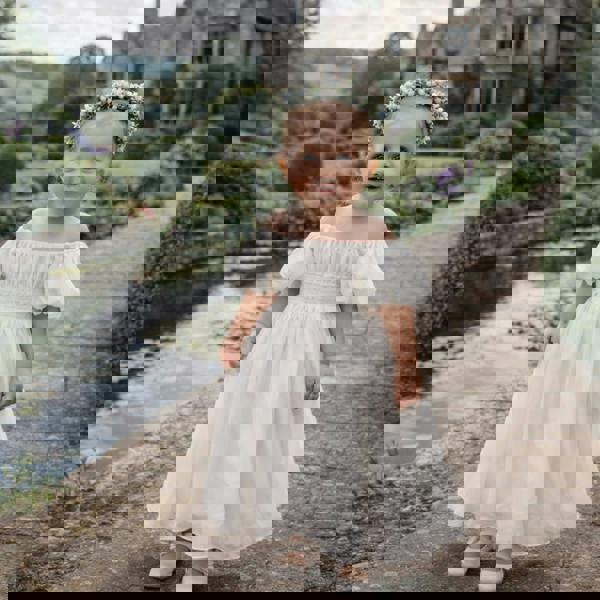 Baby girl wearing her Raye dress in pretty stately grounds
