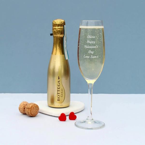 An engraved Personalised Valentine's Flute reading Olivia Happy Valentine's Day Love Sam x filled with sparkling wine next to a mini gold Bottega bottle.