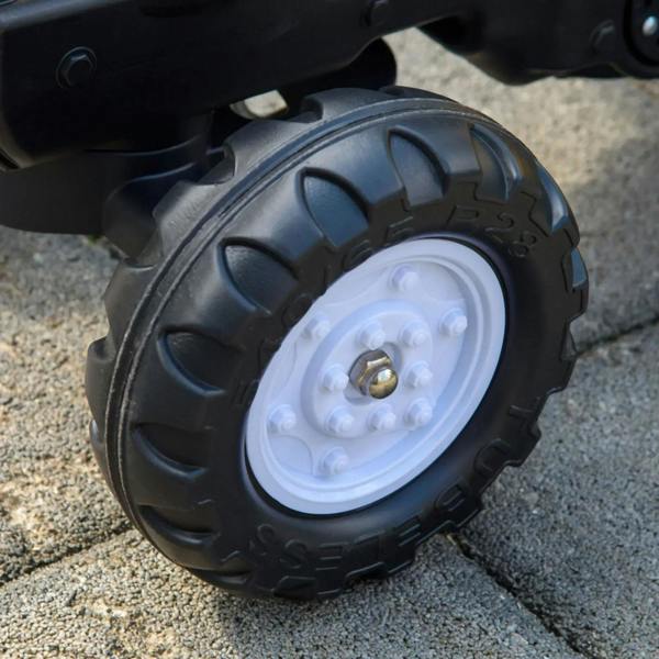 Large black plastic tire with white wheel hub on ride-on construction tractor