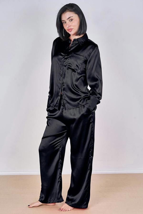 Woman wearing a black satin pajama set against a plain background