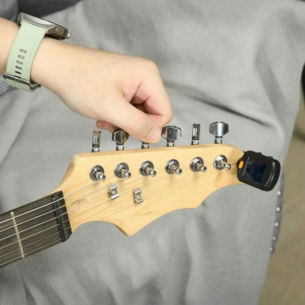 Electric guitar headstock and control knobs with hand adjusting volume, dark finish