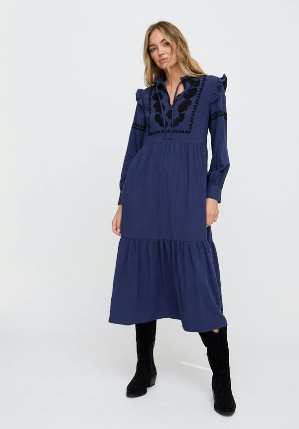 Woman wearing a blue dress with black embroidery on a white background