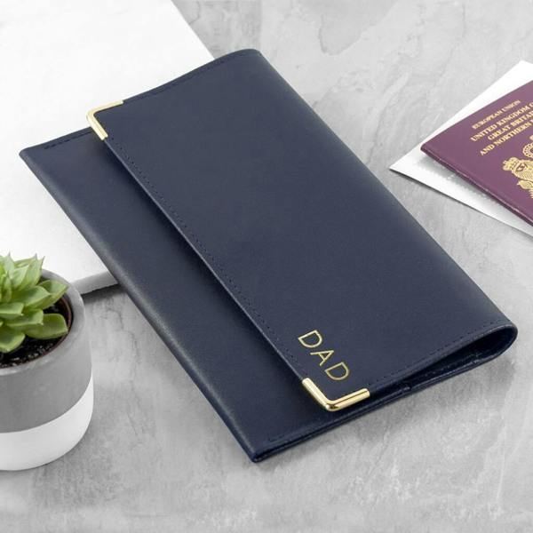 Personalised navy blue Italian leather travel organiser with gold foil initials DAD and gold metal corner details alongside a UK passport