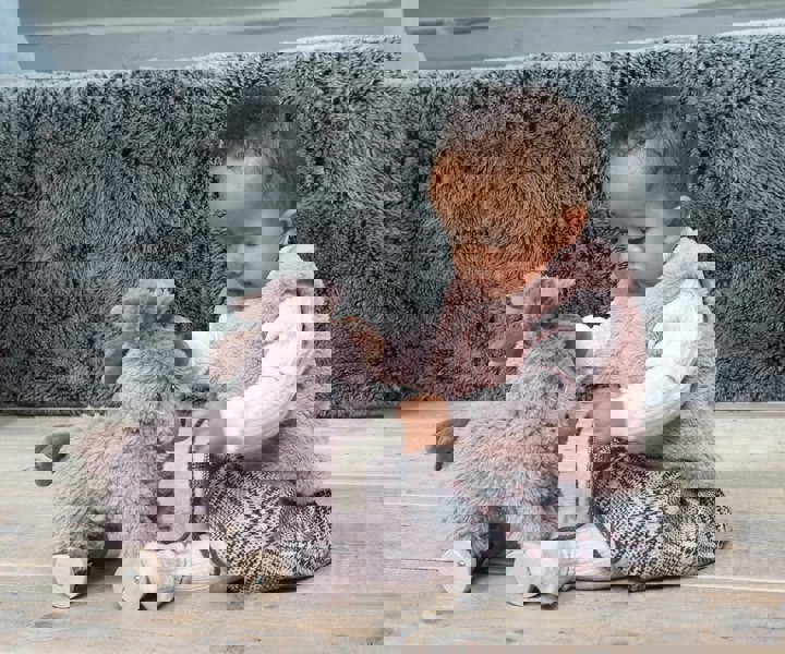 Infant girl sits on the floor playing with Norbert Donkey Pull Along Toy with removable wheels