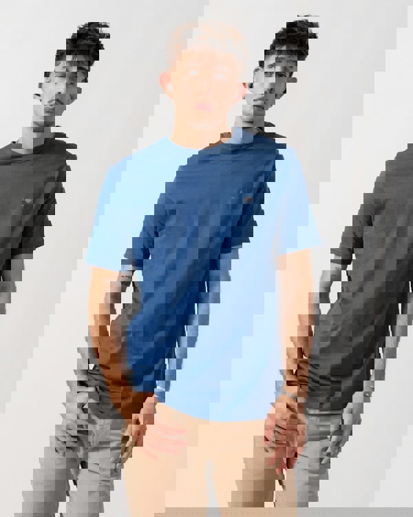 Model wearing a GANT Mens Regular Fit Short Sleeve Shield Logo T-Shirt in Vintage Blue