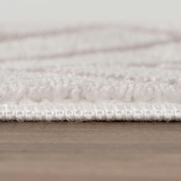 Close-up of a textured white rug on a wooden floor