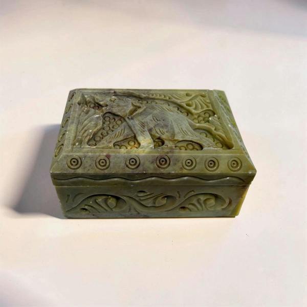 Decorative stone box with intricate carvings on a light background