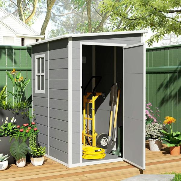 Grey storage shed with open side door, showing yard tools inside on floor