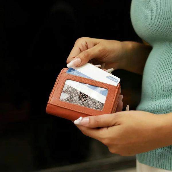 Person holding a cognac wallet with cards against a dark background
