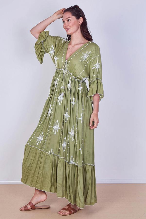 Woman wearing a green dress with white floral patterns on a plain background