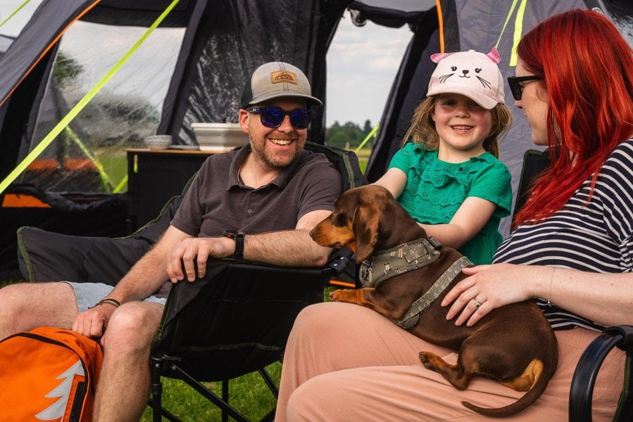 A young family sit outside the Discovery 6 Berth Inflatable Tent on a campsite