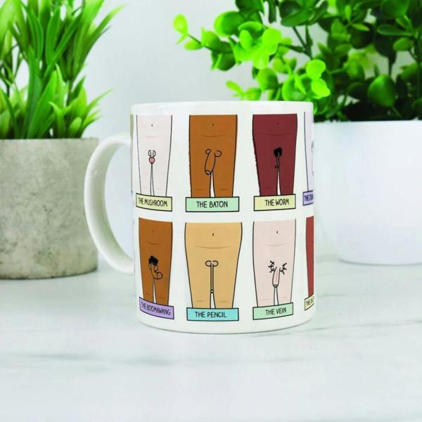 A white ceramic mug featuring a grid of comical line illustrations with funny text labels like The Mushroom and The Baton, set against a marble surface with plants.