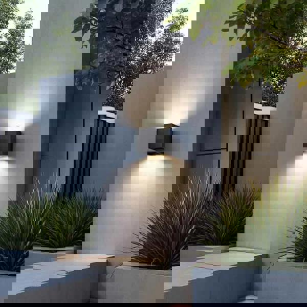 black up and down outdoor wall light mounted on the white exterior wall of a modern home 