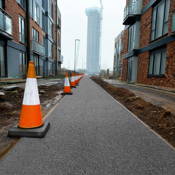 Construction cones on a grey walkway site mat with modern buildings in the background.
