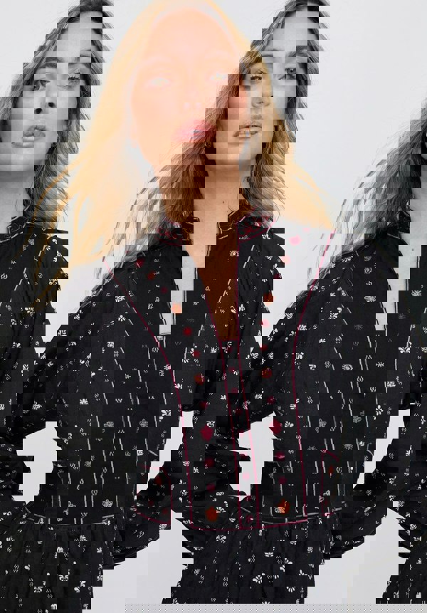 Woman wearing a black dress with floral embroidery on a white background