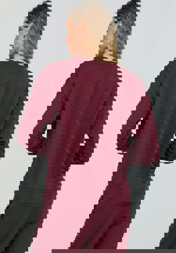 Person wearing a burgundy sweatshirt and pants on a white background