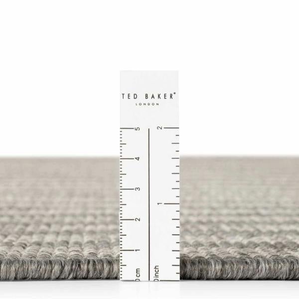 Gray textured rug with a ruler and 'Ted Baker' branding on a white background