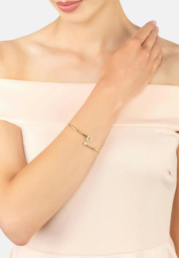 Gold bracelet on a person's wrist with a plain background