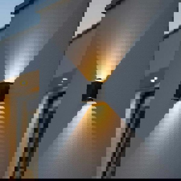 black up and down outdoor wall light mounted on the exterior of a modern house on a textured wall 