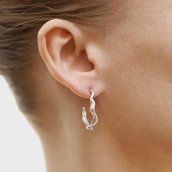An ear with a wavy silver hoop earring.