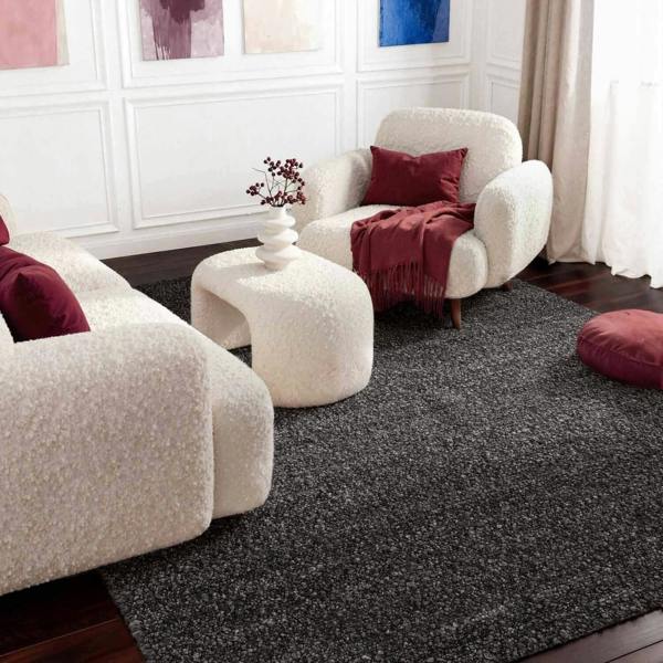 Living room with white armchairs, a small table, and red cushions on a dark gray carpet.