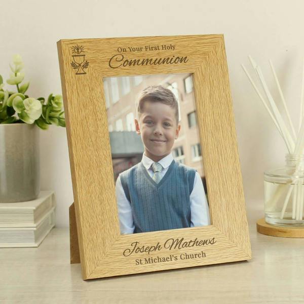 A portrait-oriented oak veneer photo frame displaying a young boy in a communion outfit, engraved with a chalice motif and custom text at the bottom.