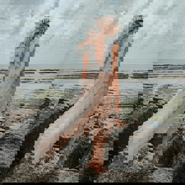 girl standing on rock on beach in a Baby Bohemian Serendipity Dress - Blush