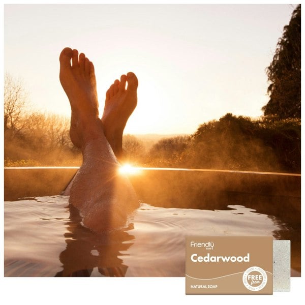 A person’s legs hanging out of a hot tub with a sunset 