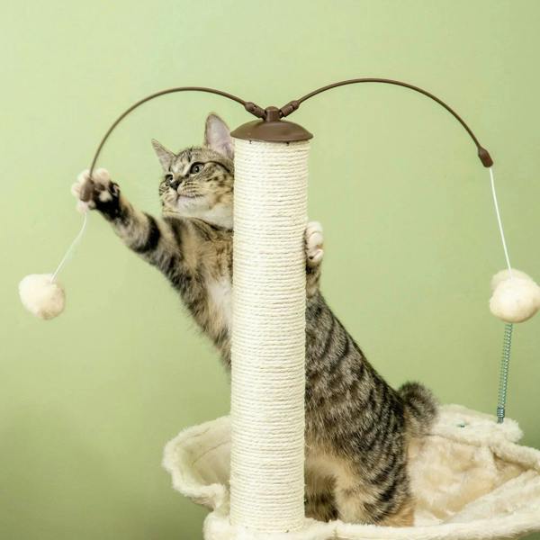 Beige cat tree with tall post and hanging toy balls, with a tabby cat playing