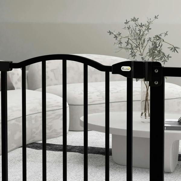 Black pet gate with arched top and side latch detail near a living room sofa