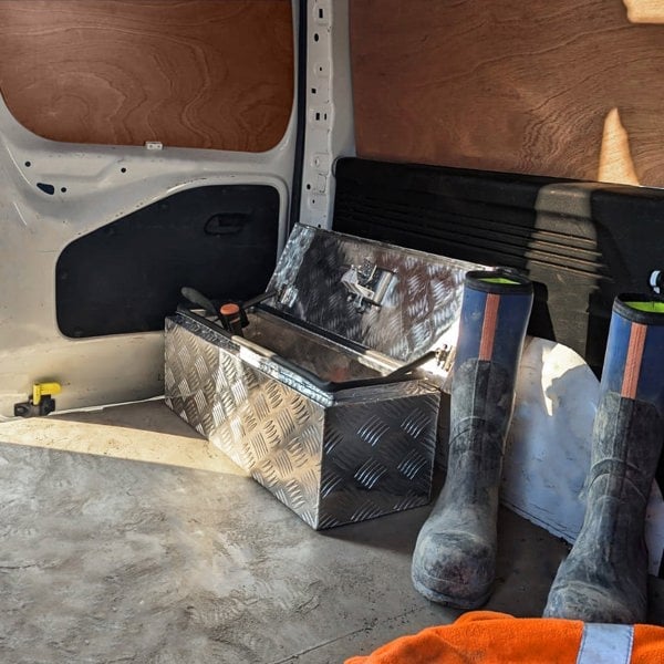 Aluminium tool box 35L with a diamond plate finish, placed in a van beside rubber boots and an orange work towel