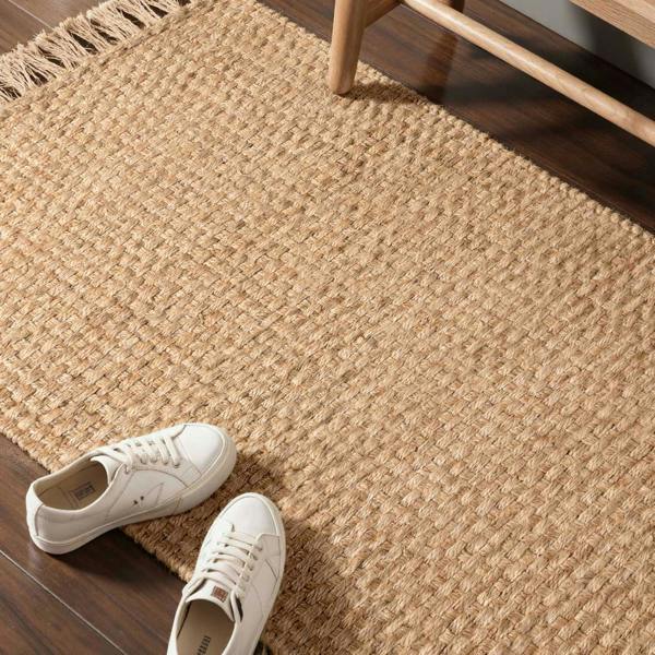White sneakers on a textured beige rug with wooden furniture.
