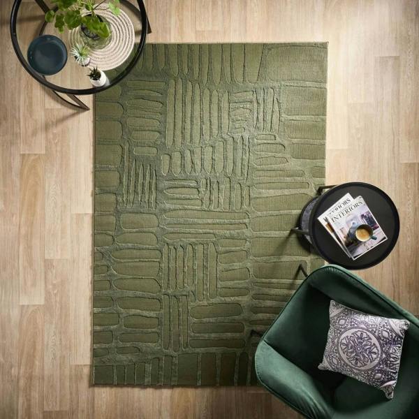 Green textured rug on a wooden floor with a green chair and small table.