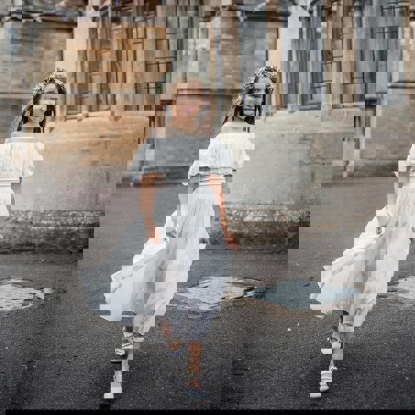 Young girl in a white dress standing in front of a historic building.