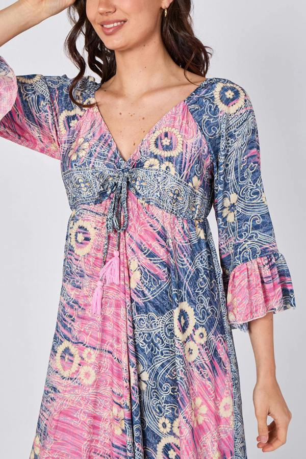 Woman wearing a colorful patterned dress with long sleeves on a plain background