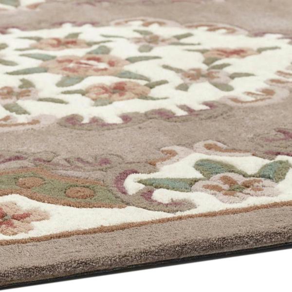 Close-up of a floral patterned rug with beige, green, and brown colors.