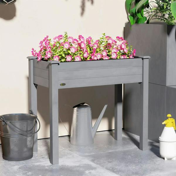 Dark grey elevated planter box with pink flowers and metal watering items beneath.
