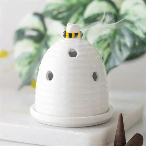 White bee-hive incense cone holder with striped top and brown incense cones on base
