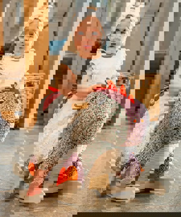 Little girl sitting on a dinosaur rocker