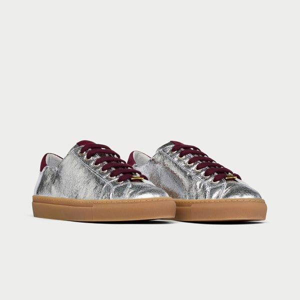 Silver star sneakers with burgundy laces on a light gray background