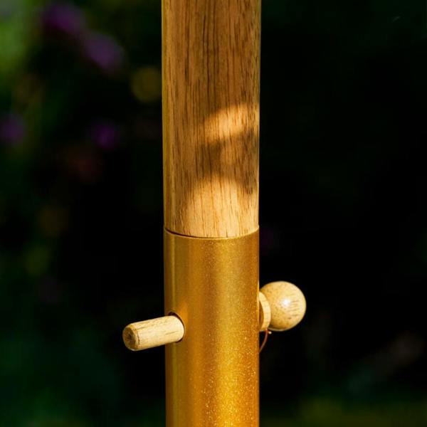 A close-up shot of the central pole assembly on the Sunningdale garden parasol. The natural grain of the upper teak wood pole slots into a metallic gold-painted connector collar, secured firmly in place with a smooth wooden locking peg.